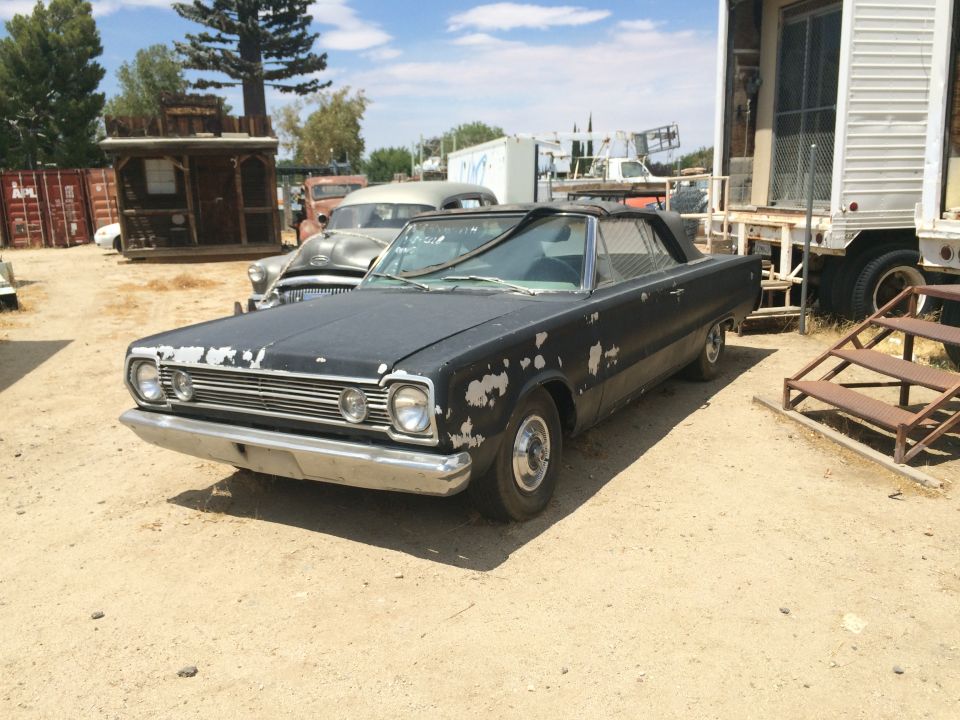 Black 1966 Plymouth Belvedere with chipped paint in a yard