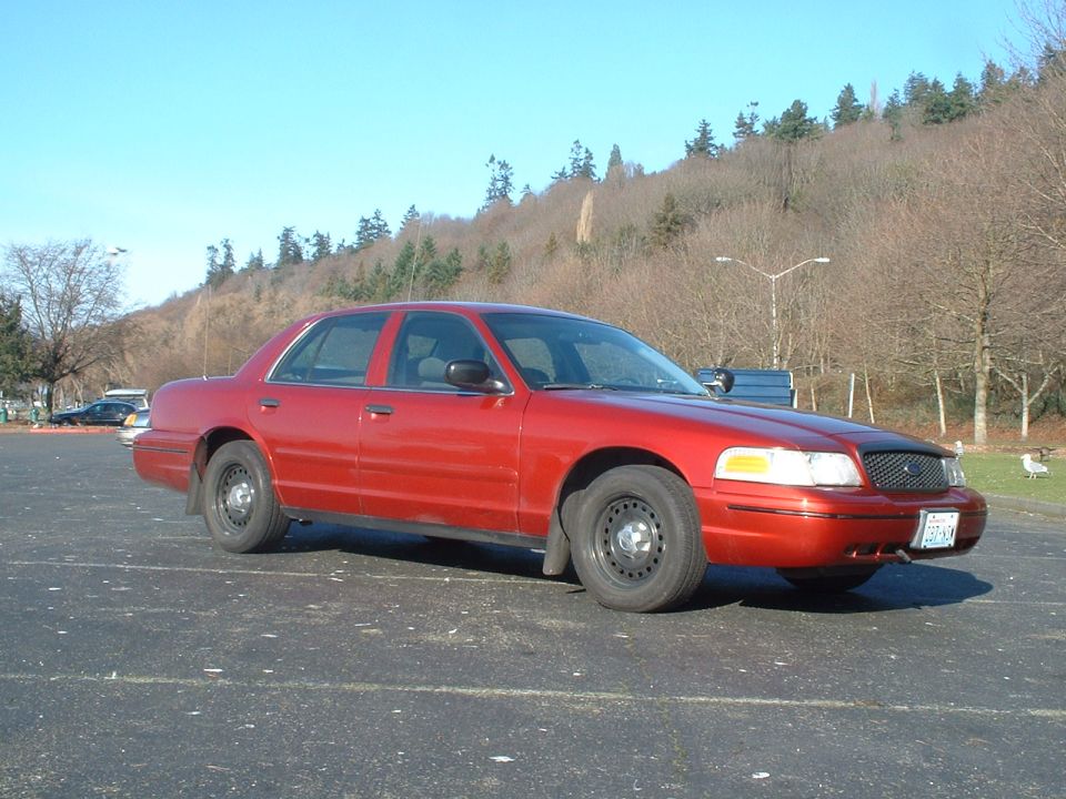 Red sedan parked in a lot, facing right. Black grille, steel wheels