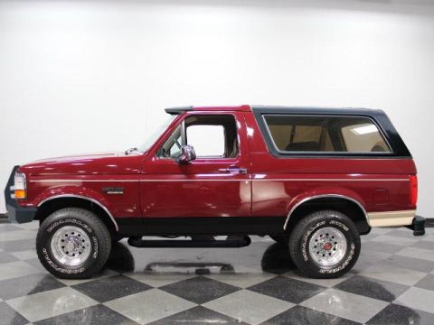 1994 Ford Bronco - Clean side profile of a dark red full-size Ford Bronco with a black lower two-tone stripe, tan accent trim, and a black removable hardtop,…