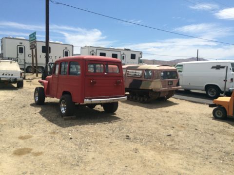 1968 Ford Mustang - Photograph of a red Willys-style wagon beside a camouflage tracked half-track vehicle outdoors.