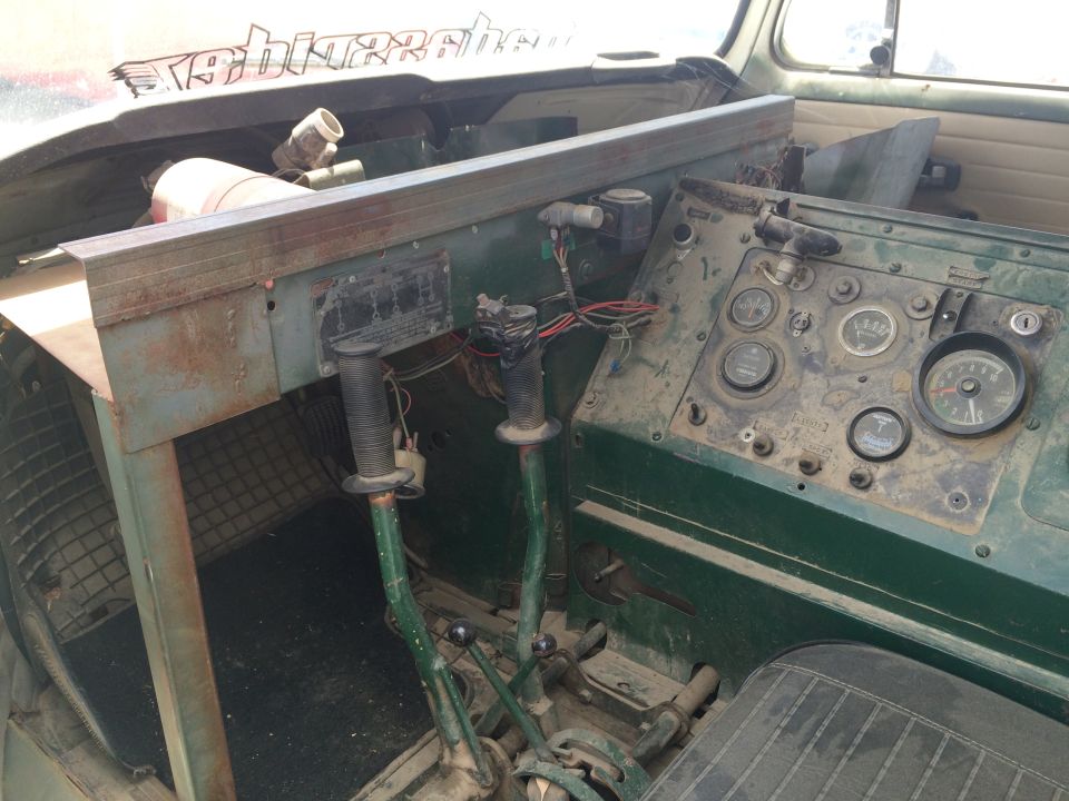 Photo of a vintage military vehicle interior with gauge panel and twin shifters