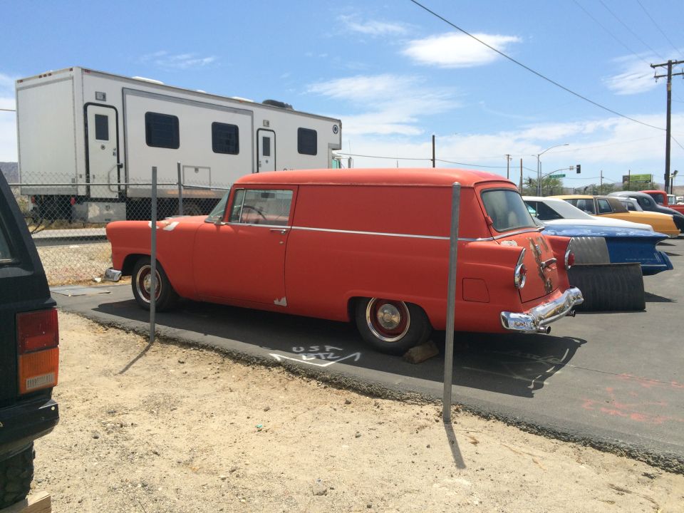 Photo of an orange 1950s sedan delivery panel car parked at a lot