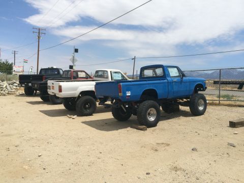 1968 Ford Mustang - Photograph of three lifted mini-trucks parked in a row in a desert dirt lot.