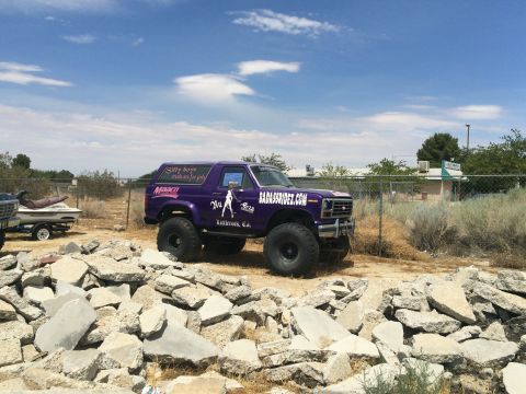 1968 Ford Mustang - Photograph of a purple lifted Ford Bronco with advertising graphics parked on rocky ground.