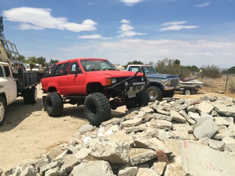 1968 Ford Mustang - Photograph of a red lifted Toyota 4Runner and other 4x4 trucks parked on rocky dirt ground.