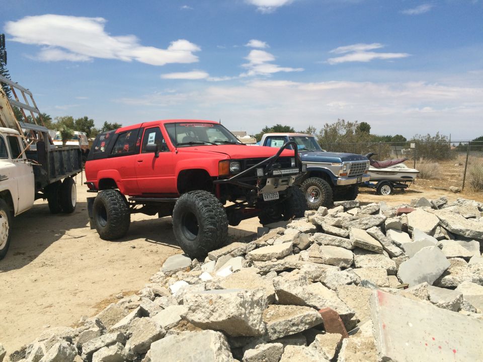 Photo of a red lifted Toyota 4Runner and other trucks in a dirt lot
