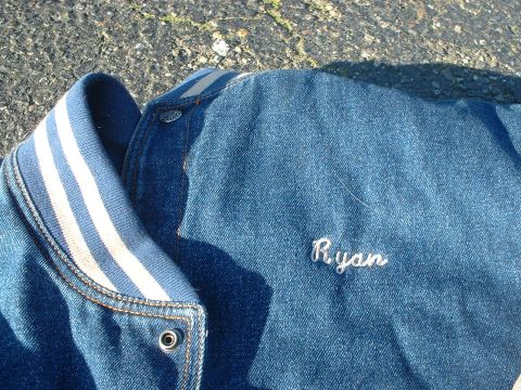 1999 Ford Crown Victoria - Denim jacket with embroidered name 'Ryan' and striped collar, lying on asphalt.