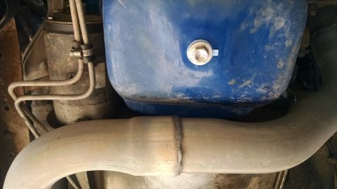 1979 Ford F-150 - A close-up, low-angle view of the underside of a vehicle, showing a portion of the exhaust system and a blue component, possibly part of th…