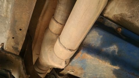 1979 Ford F-150 - A close-up, low-angle view of the underside of a vehicle, showing the exhaust pipes and a section of the frame. The exhaust pipes appear to…