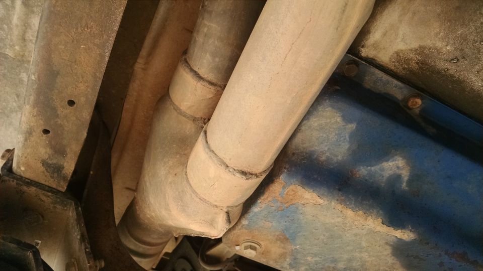 Underside of a vehicle showing exhaust pipes and frame
