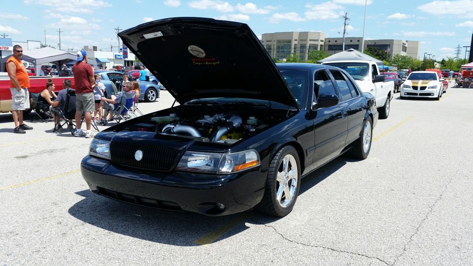 Black 2003 Mercury Marauder with hood open, showing engine, at a car show.
