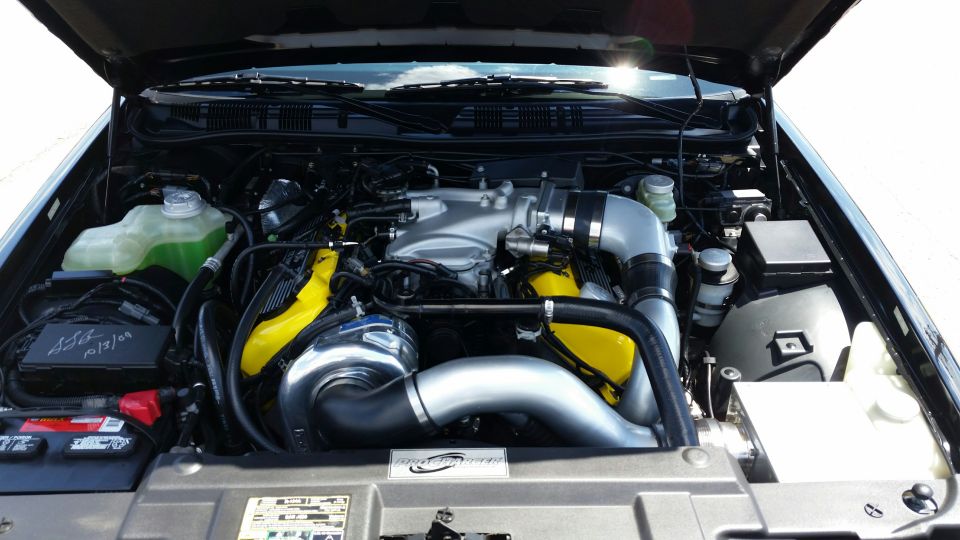 Black Mercury Marauder engine bay with supercharger and yellow accents.