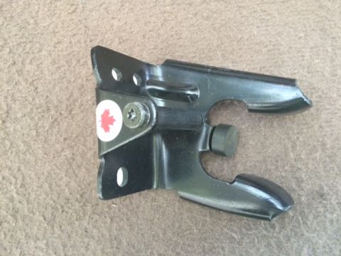 1994 Ford Bronco - A black metal bracket with a red maple leaf sticker is shown against a brown textured background. The bracket has several holes and a screw…