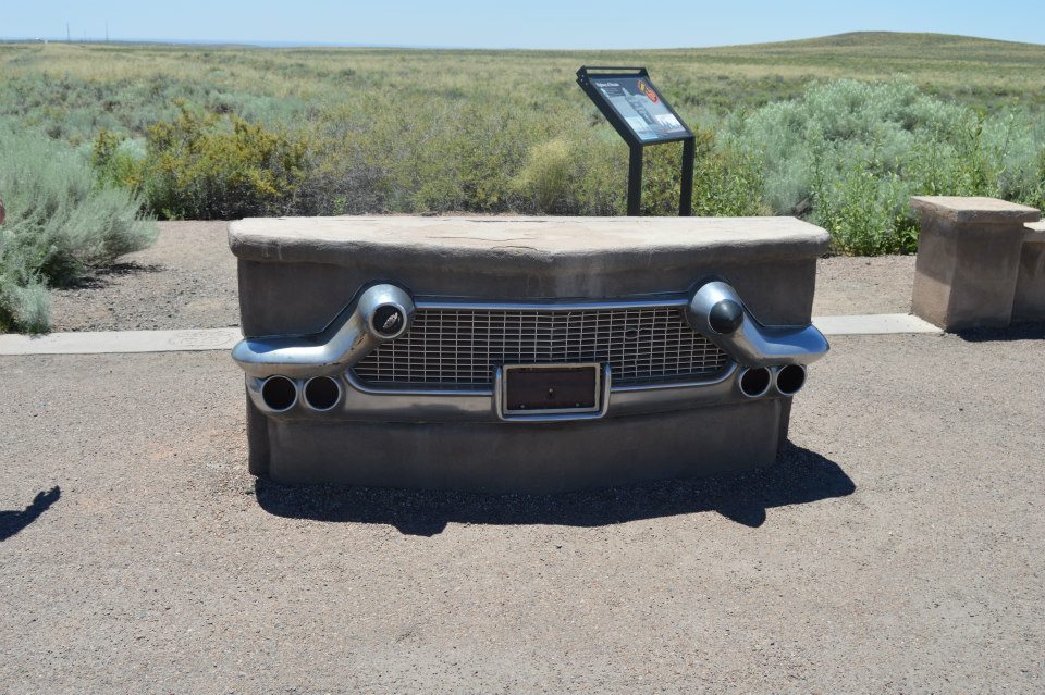 Concrete bench shaped like a vintage car grill and bumper with exhaust pipes.