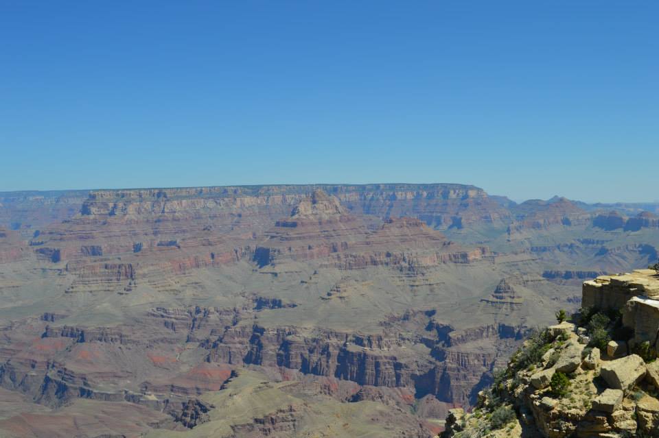 Grand Canyon landscape with layered rock formations and a rocky cliff.