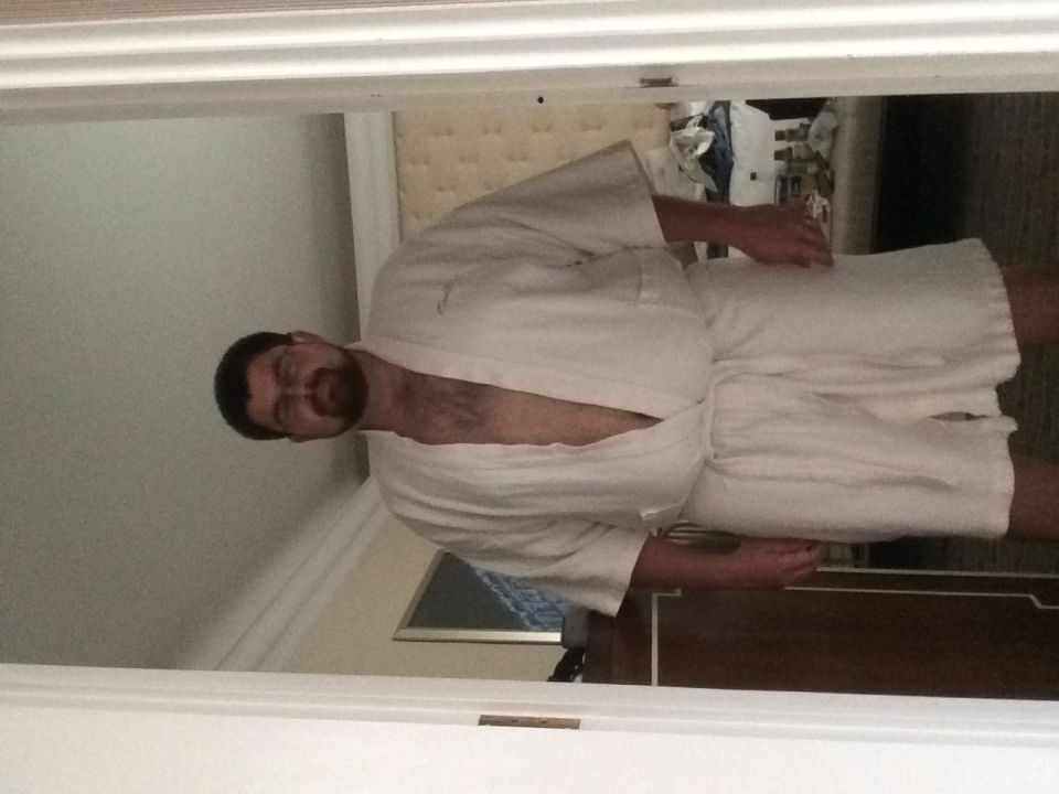 Photo of a man standing in a doorway wearing a white bathrobe in a hotel room