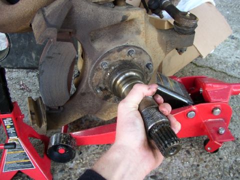 1989 Ford Bronco - Installing a stub shaft on a vehicle's front axle, supported by jack stands and a floor jack.