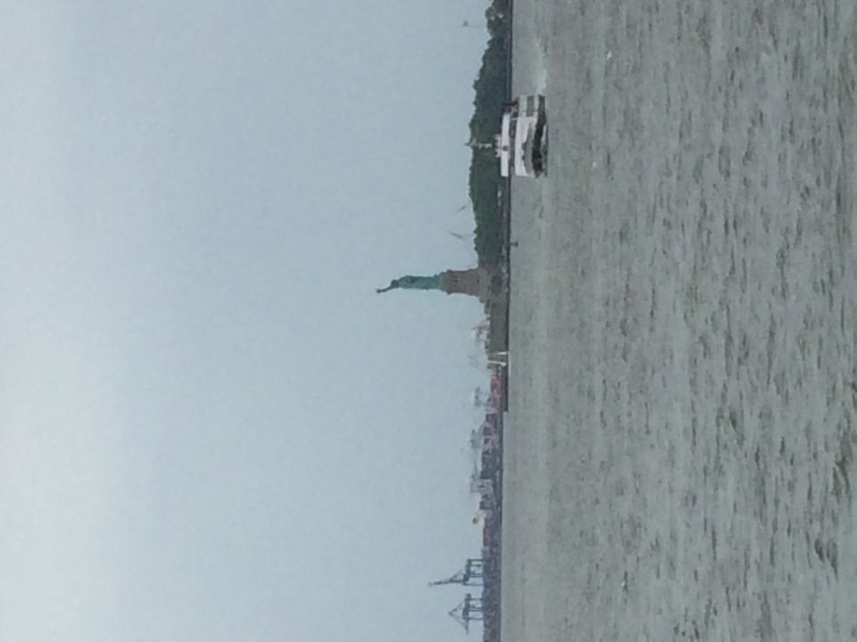 Statue of Liberty and a passing ferry across the harbor