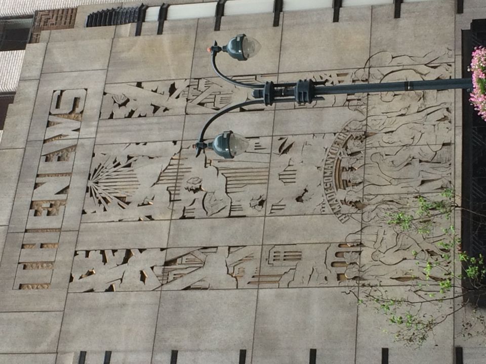 Art Deco carved stone facade of The News building with a street lamp in front