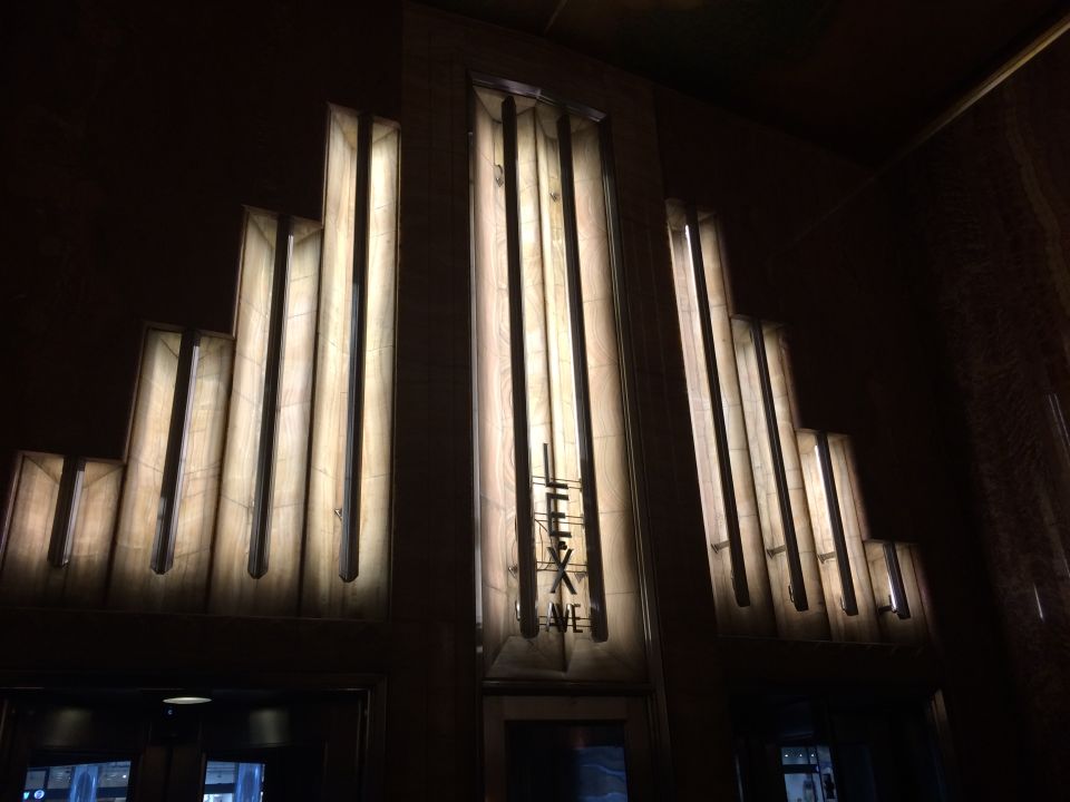 Illuminated Art Deco stepped wall sconces in a darkened building lobby
