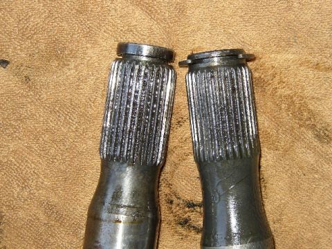1989 Ford Bronco - Close-up of two axle shafts, likely for a vehicle's drivetrain, resting on a textured surface.