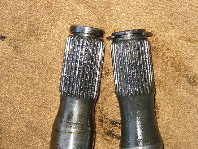 Two splined axle shaft ends compared side by side on a shop towel