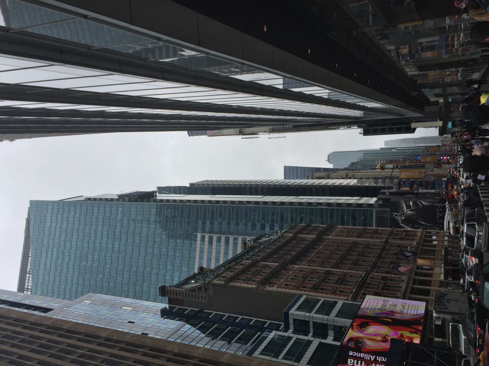 Manhattan street canyon between glass and stone skyscrapers under gray sky