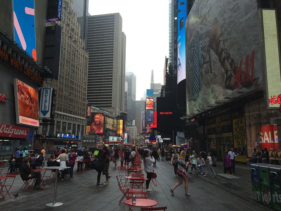 Times Square plaza crowded with people, tables and billboards