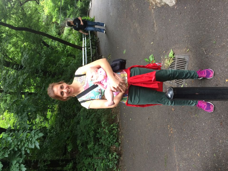 Smiling woman holding a baby on a wooded Central Park walkway