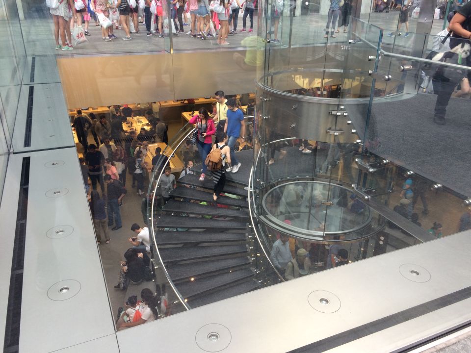 Spiral glass staircase inside a busy Apple Store