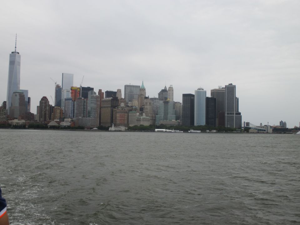 New York City skyline with One World Trade Center and other skyscrapers across the water under a cloudy sky