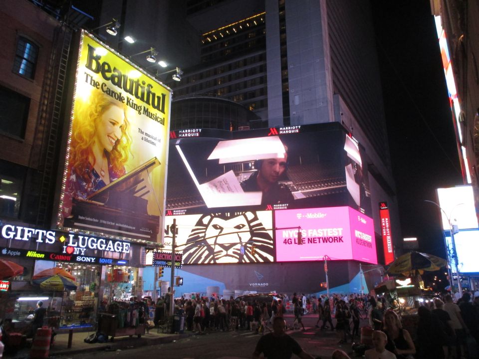 Times Square billboards at night with crowds below