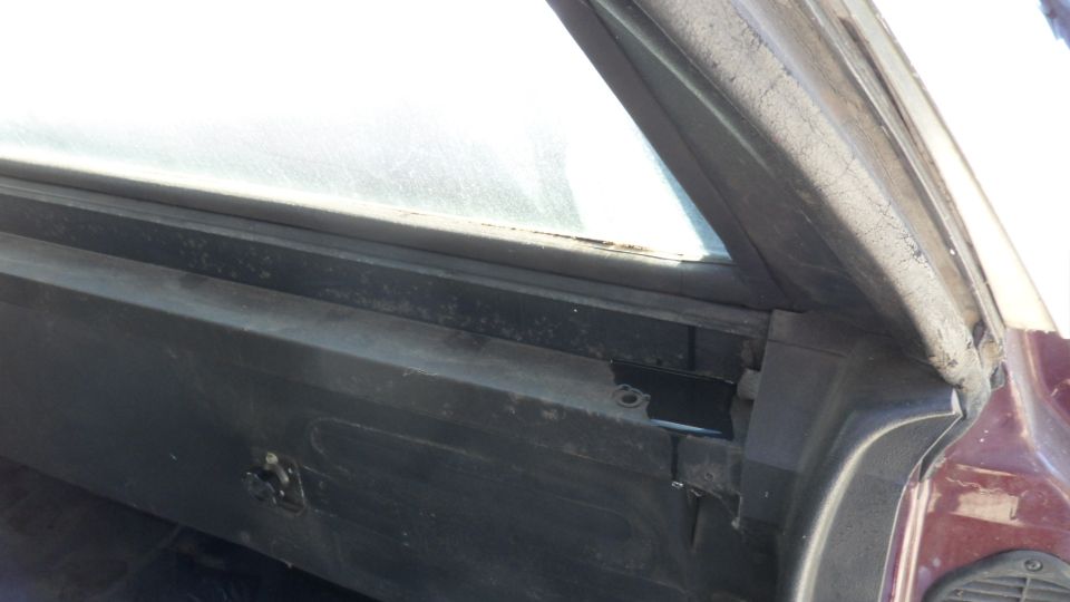 Close-up of a car's interior door frame and window seal. Shows some wear and tear