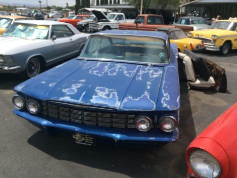 1968 Ford Mustang - This blue sedan has significant paint damage and is parked in an outdoor lot with several other vehicles.