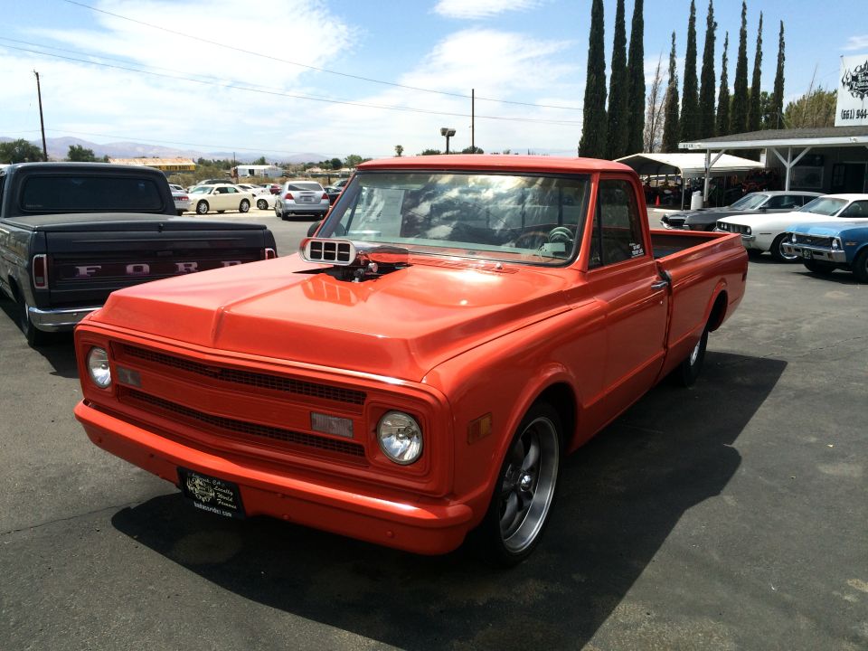 Orange pickup truck with a hood scoop, seen from the front-right