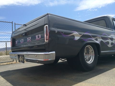 1968 Ford Mustang - Rear view of a customized Ford truck with flame decals and a chrome bumper under a bright blue sky.