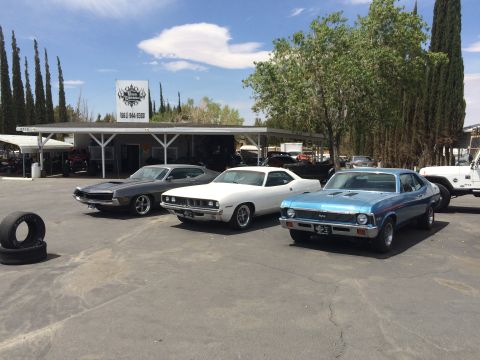 1968 Ford Mustang - A blue 1970 Chevrolet Nova SS is parked in a lot alongside a white Plymouth Barracuda and a gray muscle car.