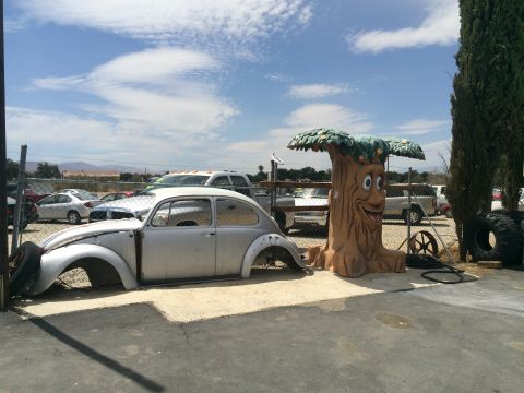 1968 Ford Mustang - A stripped-down Volkswagen Beetle body sits in a lot, accompanied by a whimsical tree decoration.