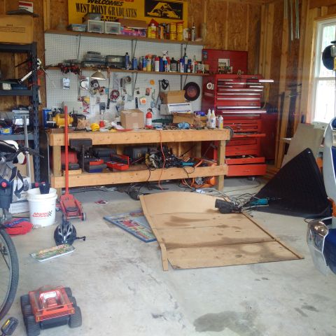 1978 Ford Bronco - A cluttered garage workshop with tools and equipment organized on shelves and a workbench.