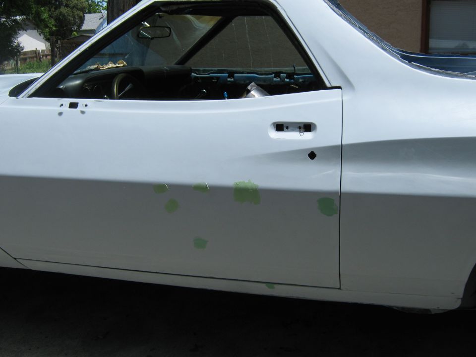 Side view of a white 1973 Ford Ranchero with primer spots on the door