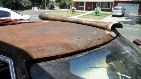 1972 Ford Ranchero - A heavily rusted car roof is visible, with a long, bent metal pipe resting on it.