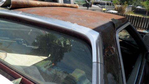 1972 Ford Ranchero - The side profile of a 1972 Ford Ranchero reveals a heavily rusted roofline and a glimpse of the interior.