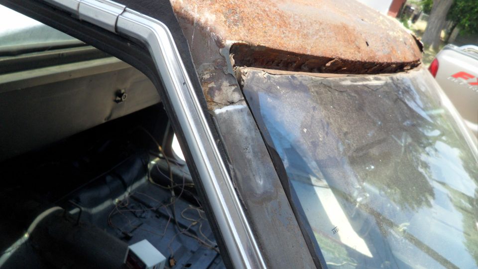 rusted car roof and windshield frame, interior visible