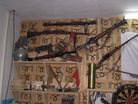 1981 Ford Bronco - A collection of historical firearms and military memorabilia is displayed on a wall of wooden crates.