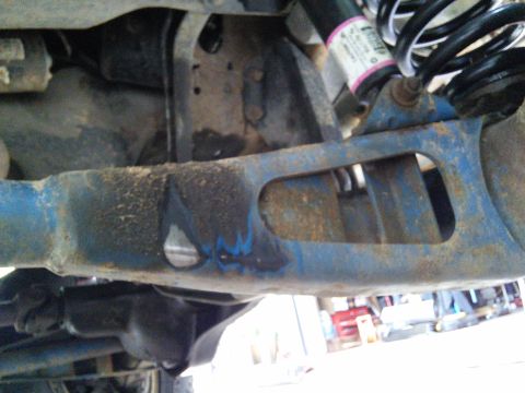 1996 Ford Bronco - Close-up view of the vehicle's suspension system, highlighting the blue-painted arm and shock assembly.