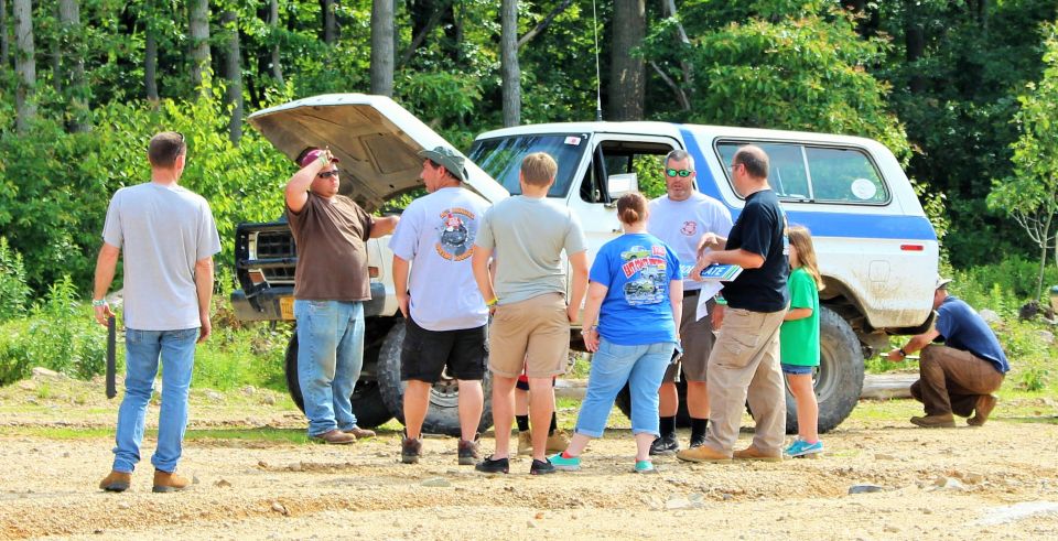 White SUV with hood open, group of people standing around it outdoors