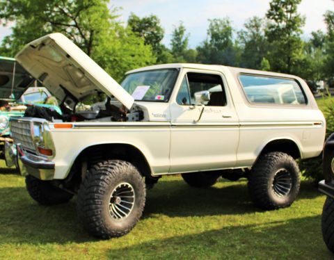 1979 Ford Bronco - A white 1978 Ford Bronco is displayed with its hood open, its lifted suspension and large tires.