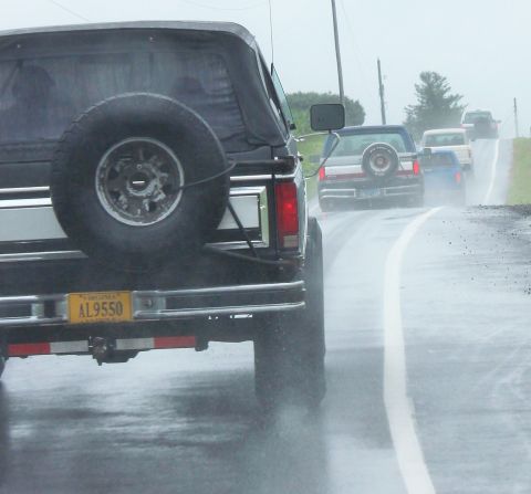 1979 Ford Bronco - A line of vehicles, including a Ford Bronco, travel down a wet highway in the rain.