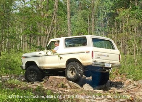 1979 Ford Bronco - A 1979 Ford Bronco navigates a rocky off-road course surrounded by trees.