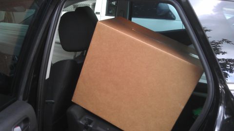 1994 Ford Bronco - A large cardboard box is loaded into the back seat of a car, obscuring the view of another vehicle outside.